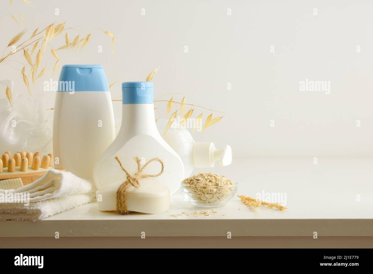 Prodotti per doccia con estratto di avena in contenitori con elementi per l'igiene personale su tavola bianca. Vista rialzata. Composizione orizzontale. Foto Stock