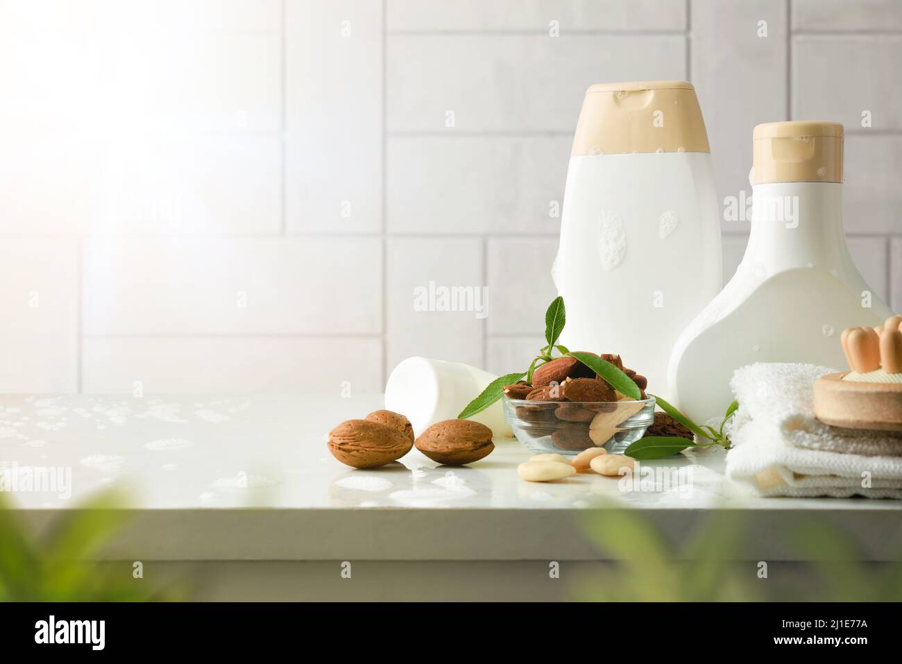 Prodotti da bagno con estratto di mandorle e articoli da toeletta su tavola bianca in bagno. Vista frontale. Composizione orizzontale. Foto Stock