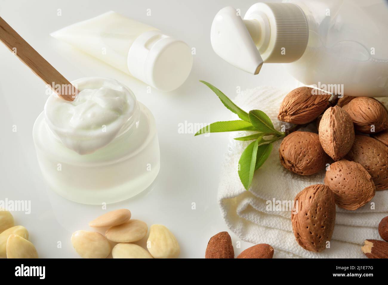 Bagno e prodotti cosmetici con estratto di mandorle e frutta e prodotti da bagno su tavola bianca in bagno. Vista rialzata. Composizione orizzontale. Foto Stock