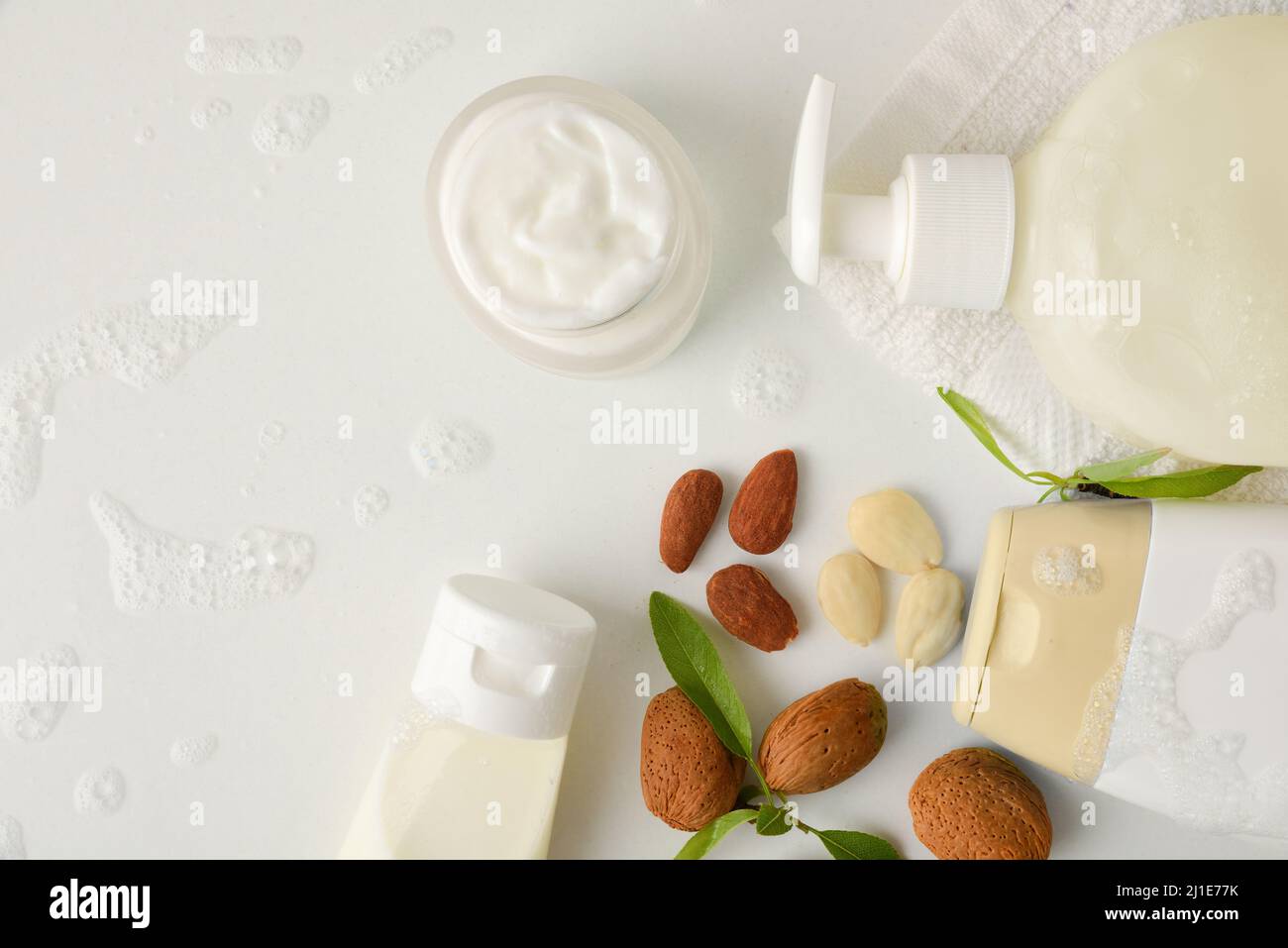 Bagno e prodotti cosmetici con estratto di mandorle e articoli da toeletta su tavola bianca in bagno. Vista dall'alto. Composizione orizzontale. Foto Stock