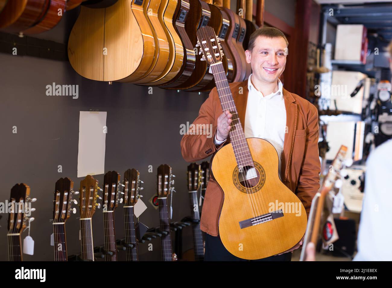 Shopman vende chitarre acustiche Foto Stock