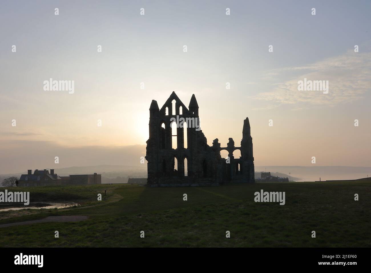 il sole che scende dietro le rovine dell'abbazia di whitby Foto Stock