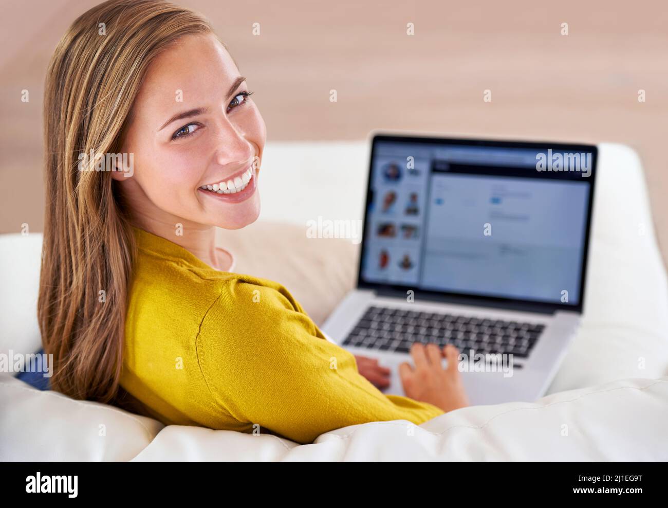 Navigare sul Web il giorno della sua partenza. Ritratto di una giovane donna attraente che usa il suo computer portatile mentre si siede sul divano a casa. Foto Stock