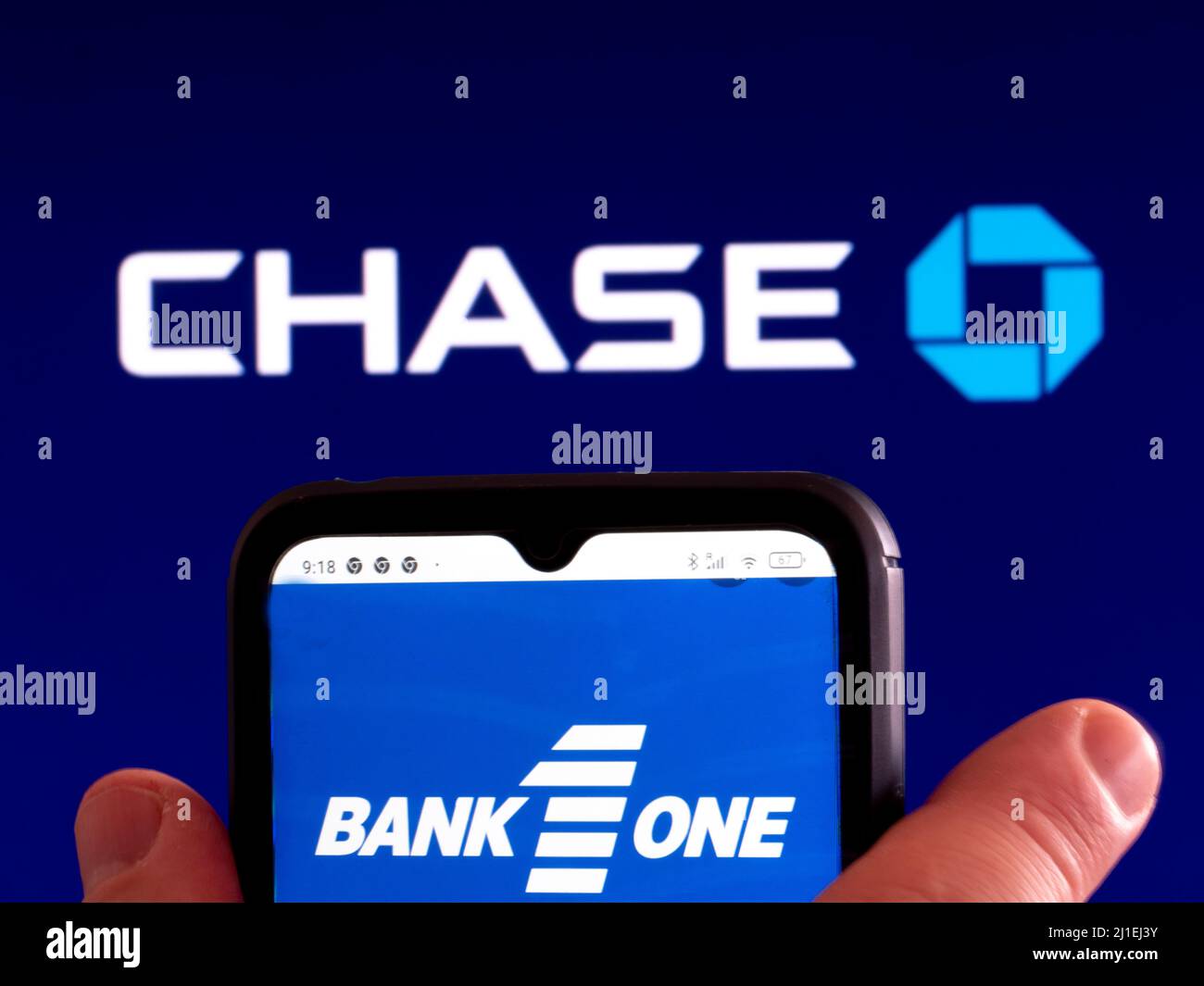 In questa foto, il logo Bank One Capital Holdings LLC viene visualizzato sullo schermo di uno smartphone con il logo JPMorgan Chase & Co sullo sfondo Foto Stock