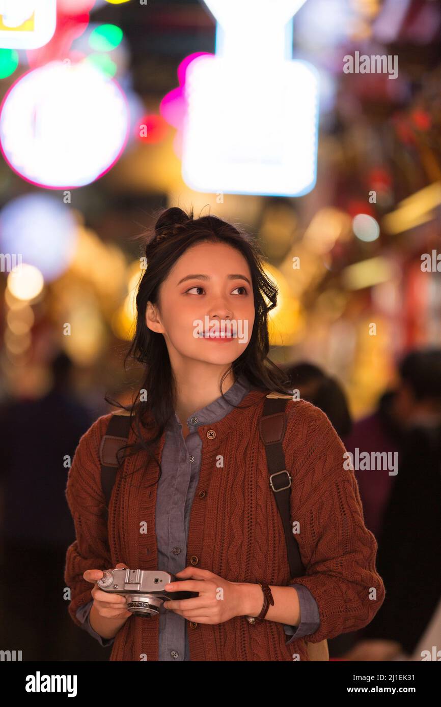 Una giovane donna che cammina sotto le luci al neon - foto d'archivio Foto Stock