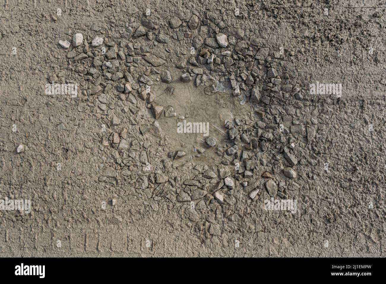 strada sterrata sgretolante senza pavimentazione asfaltata, fatta di argilla e sporcizia con macerie, con buche e buche piene d'acqua, pozzanghere bagnate dopo la pioggia Foto Stock