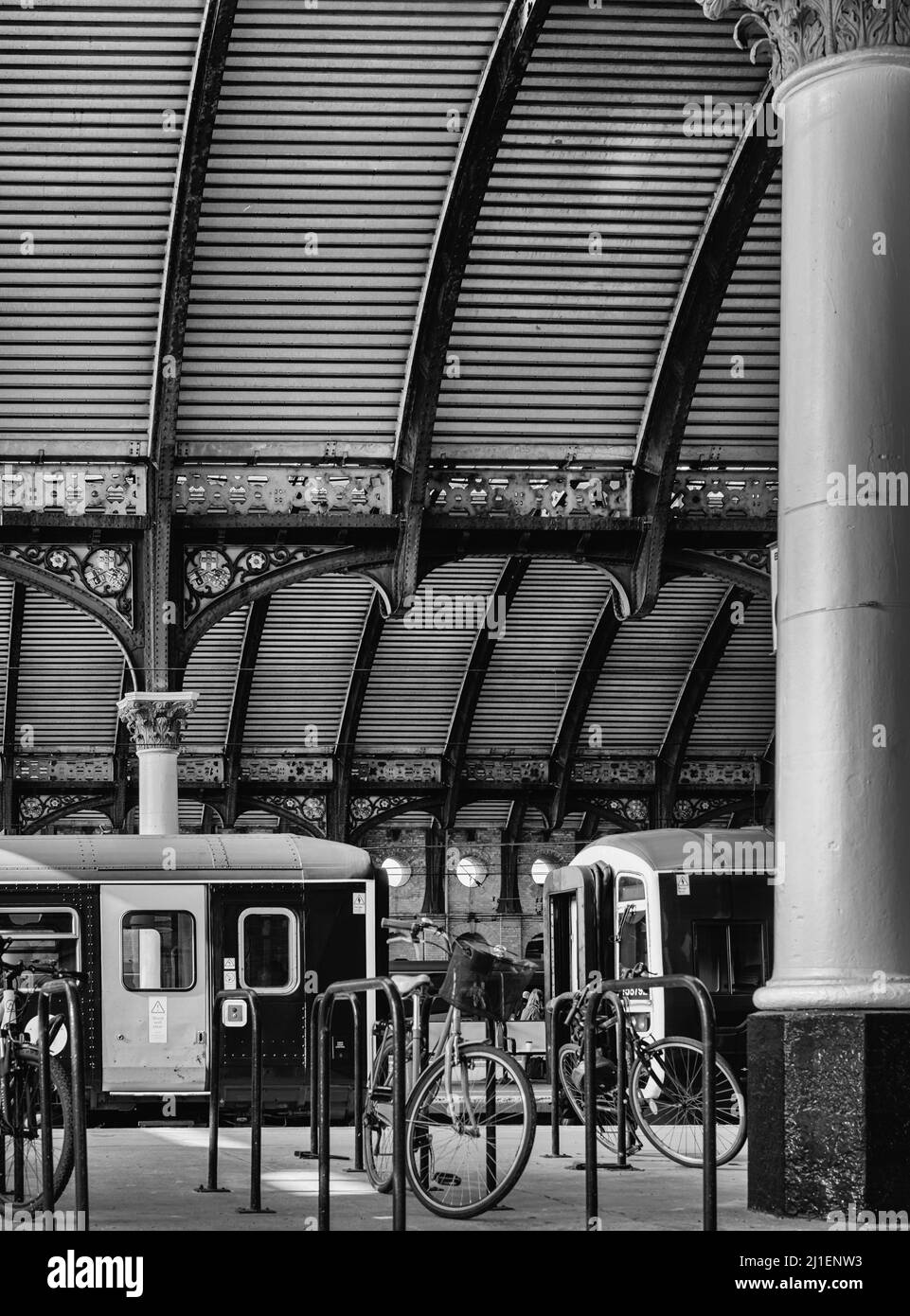 Piattaforma della stazione ferroviaria con una bicicletta in primo piano. Due treni sono dietro e una tettoia ricurva ornata del 19th secolo è in testa. Foto Stock