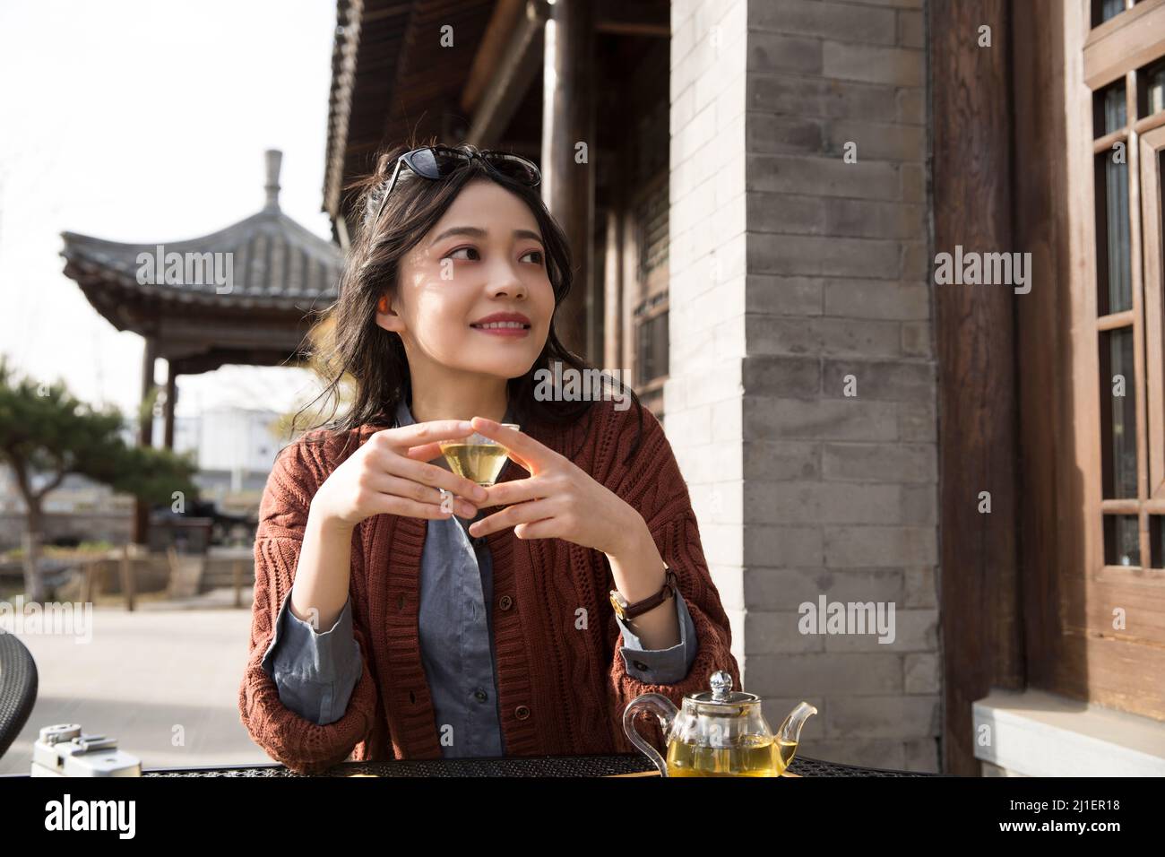 Studente universitario cinese che gusta il tè pomeridiano nel caffè sul marciapiede - foto di scorta Foto Stock