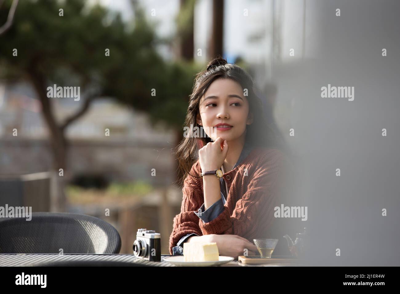 Studente universitario cinese che gusta il tè pomeridiano nel caffè sul marciapiede - foto di scorta Foto Stock