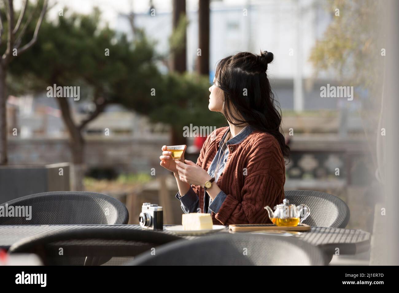 Studente universitario cinese che gusta il tè pomeridiano nel caffè sul marciapiede - foto di scorta Foto Stock