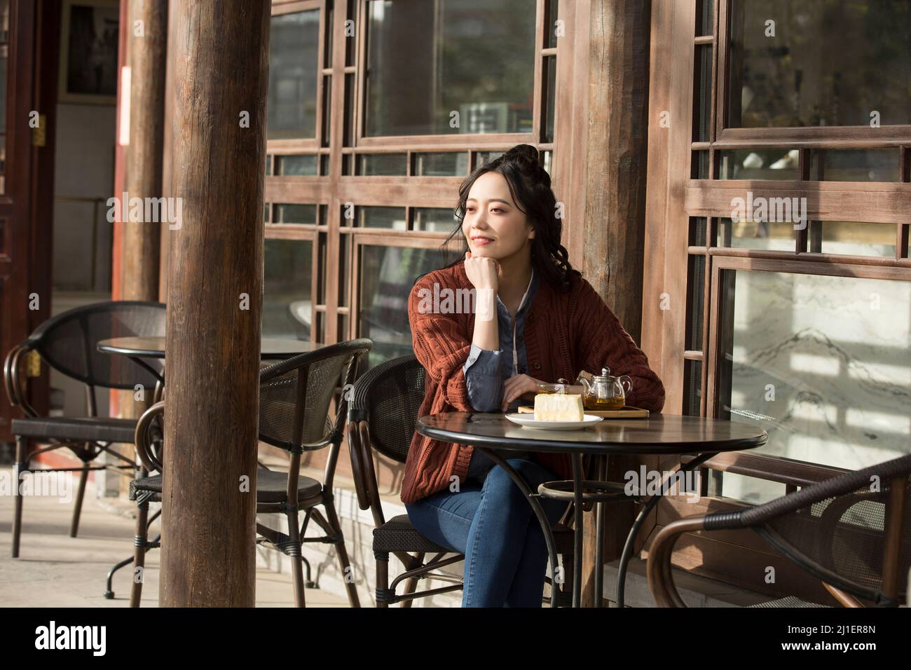 Donna cinese con colletto bianco che gusta il tè pomeridiano nel caffè sul marciapiede - foto di scorta Foto Stock