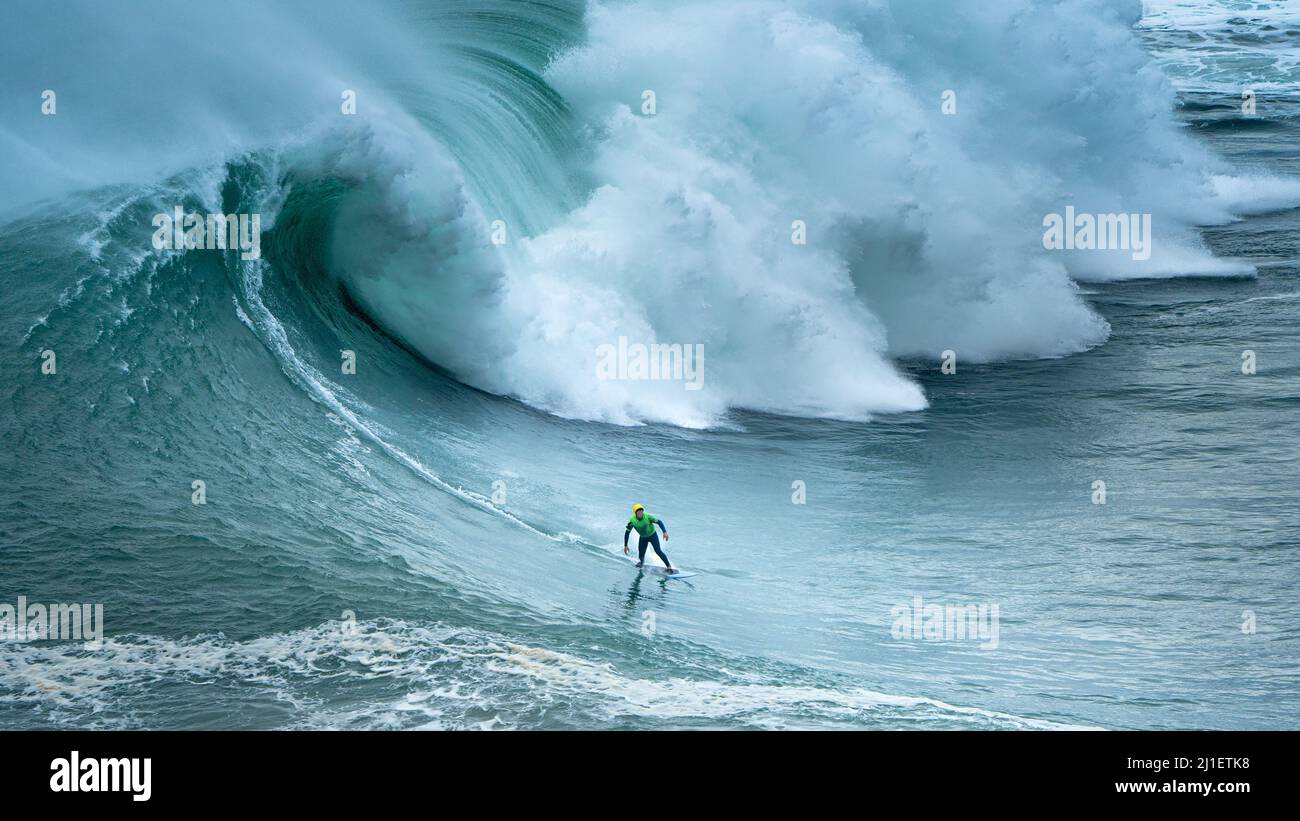 Un surfista nelle onde di Nazaré in Portogallo Foto Stock