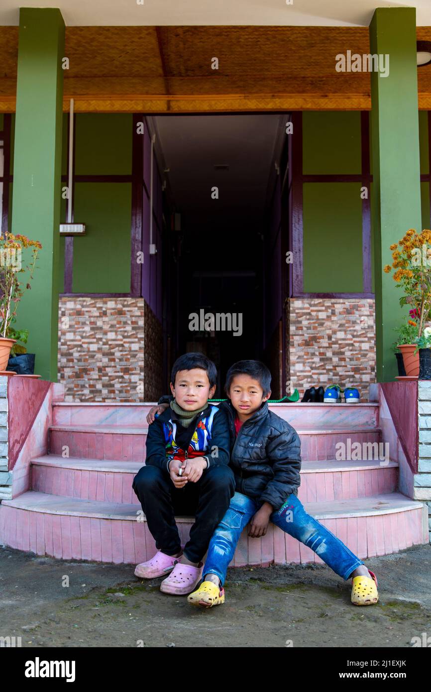 Vista di due ragazzi locali nella città di Pelling seduti sui gradini della loro casa. Foto Stock