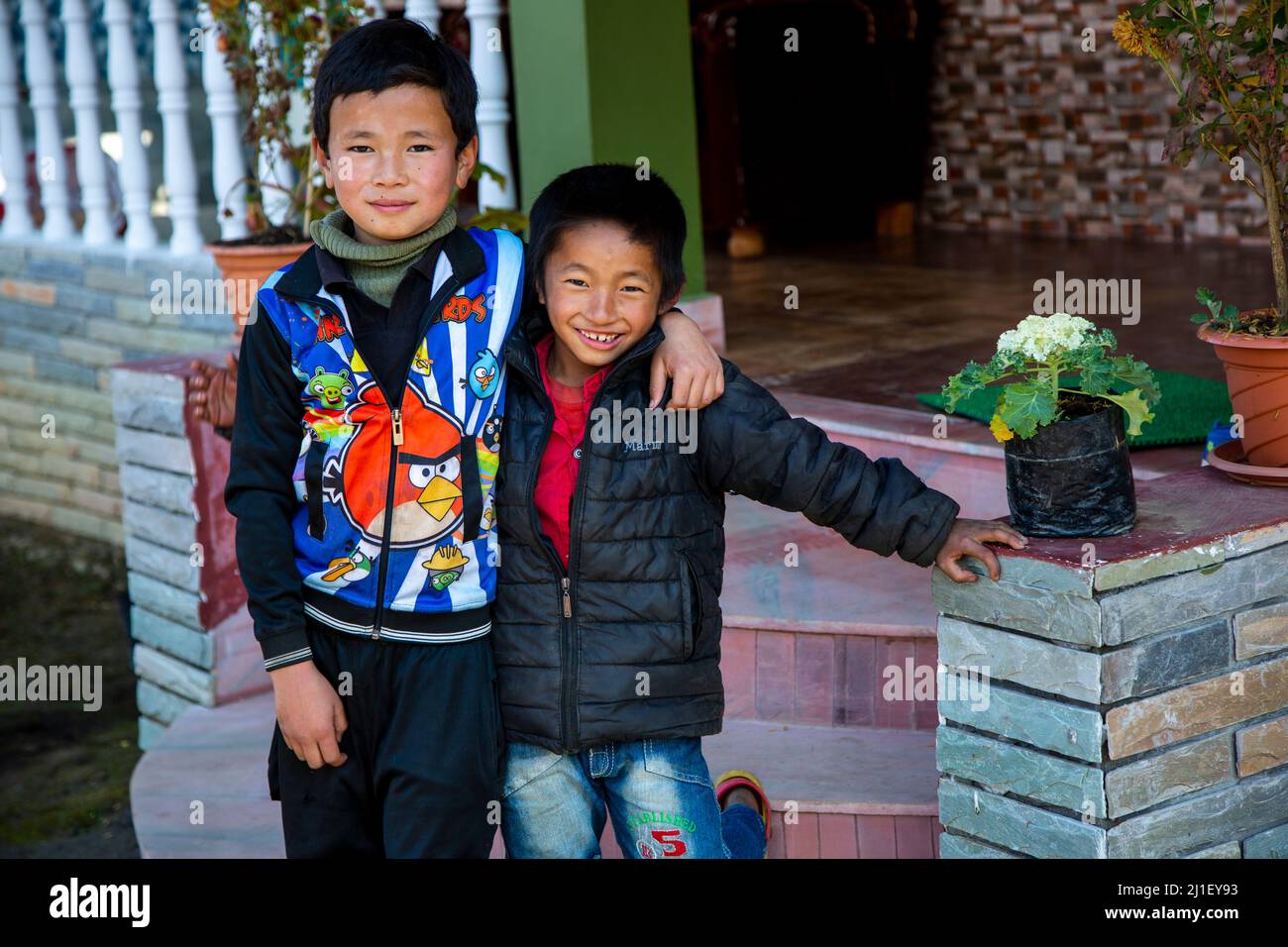 Vista di due ragazzi locali nella città di Pelling in piedi insieme sullo sfondo della loro casa. Foto Stock