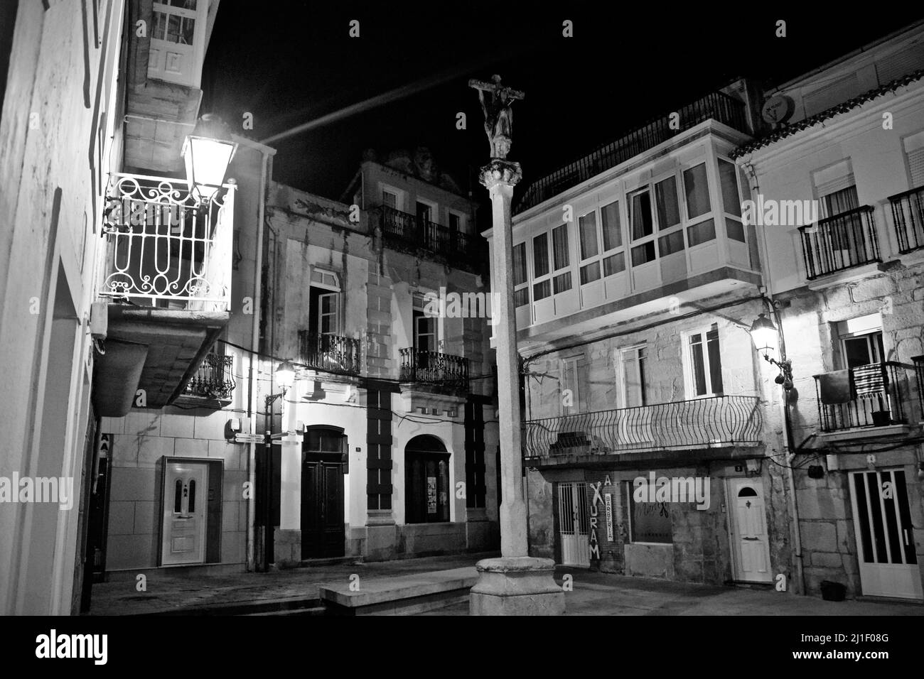 Piccola piazza deserta di notte con una croce religiosa nella piccola città di Muros Foto Stock