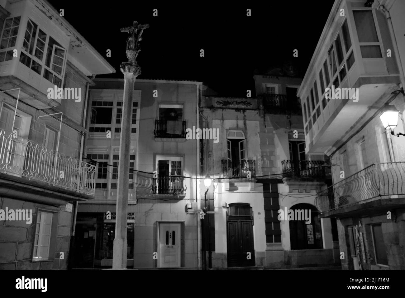 Piccola piazza deserta di notte con una croce religiosa nella piccola città di Muros Foto Stock