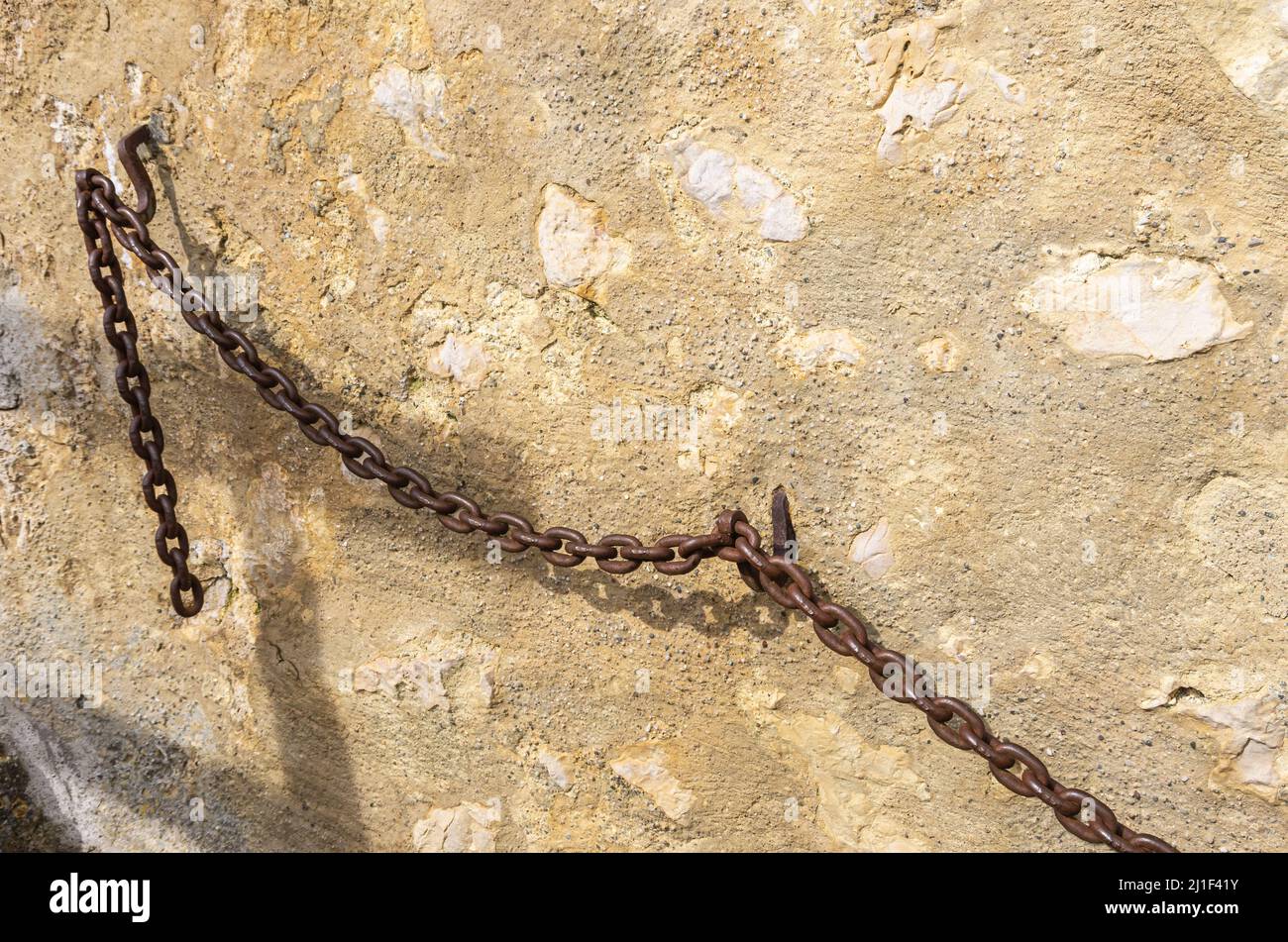 Catena di ferro pesante utilizzata come ringhiera o corrimano su una parete medievale del castello. Foto Stock