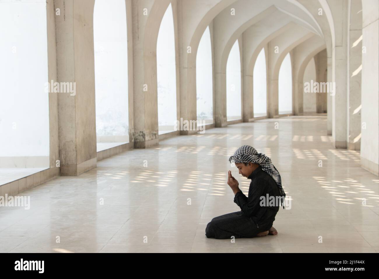 Un bambino prega alla Moschea Nazionale di Baiitul Mukarram a Dhaka, Bangladesh. La Moschea Nazionale del Bangladesh, conosciuta come Baitul Mukarram o la Casa Santa in inglese, è una delle 10 moschee più grandi del mondo e può ospitare fino a 40.000 persone, anche nello spazio aperto esterno. La moschea ha diverse caratteristiche architettoniche moderne e allo stesso tempo conserva i principi tradizionali dell'architettura Mughal, che da qualche tempo è stata dominante nel subcontinente indiano. (Foto di Joy Saha / Pacific Press) Foto Stock