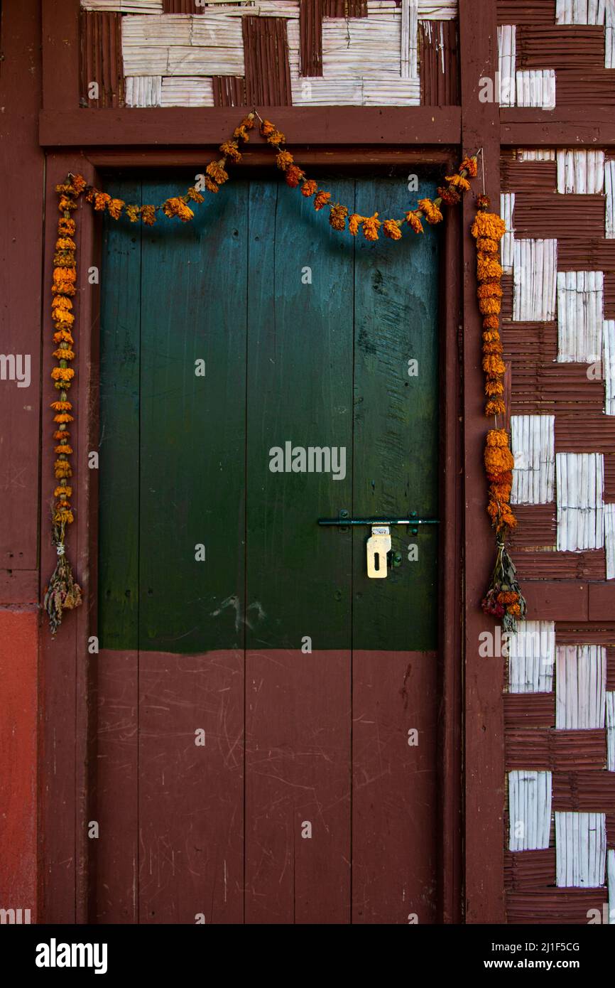 Vista ravvicinata di una porta in legno decorata con ghirlone appeso intorno ad essa. Foto Stock