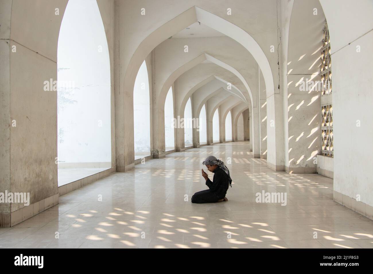 Dhaka, Dhaka, Bangladesh. 24th Dic 2021. Un bambino prega alla Moschea Nazionale di Baiitul Mukarram a Dhaka, Bangladesh. La Moschea Nazionale del Bangladesh, conosciuta come Baitul Mukarram o la Casa Santa in inglese, è una delle 10 moschee più grandi del mondo e può ospitare fino a 40.000 persone, anche nello spazio aperto esterno. La moschea ha diverse caratteristiche architettoniche moderne e allo stesso tempo conserva i principi tradizionali dell'architettura Mughal, che da qualche tempo è stata dominante nel subcontinente indiano. (Credit Image: © Joy Saha/Pacific Press via ZUMA Press Wire) Foto Stock