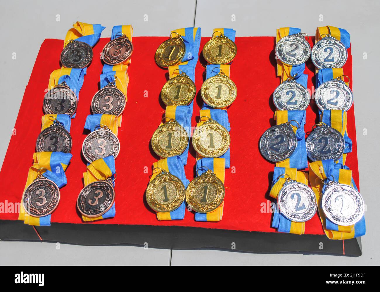 Medaglie d'oro, d'argento e di bronzo per la premiazione in concorsi per bambini con nastri giallo-blu della bandiera Ucraina Foto Stock