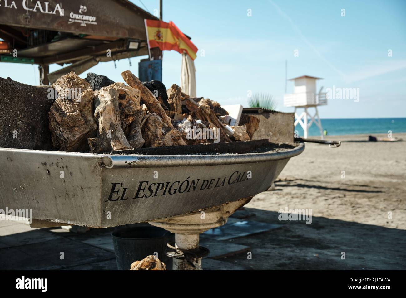 Barbecue della bancarella vendita spiedini di sardine alla griglia 'El espigón de la Cala' con una bandiera spagnola sullo sfondo Foto Stock