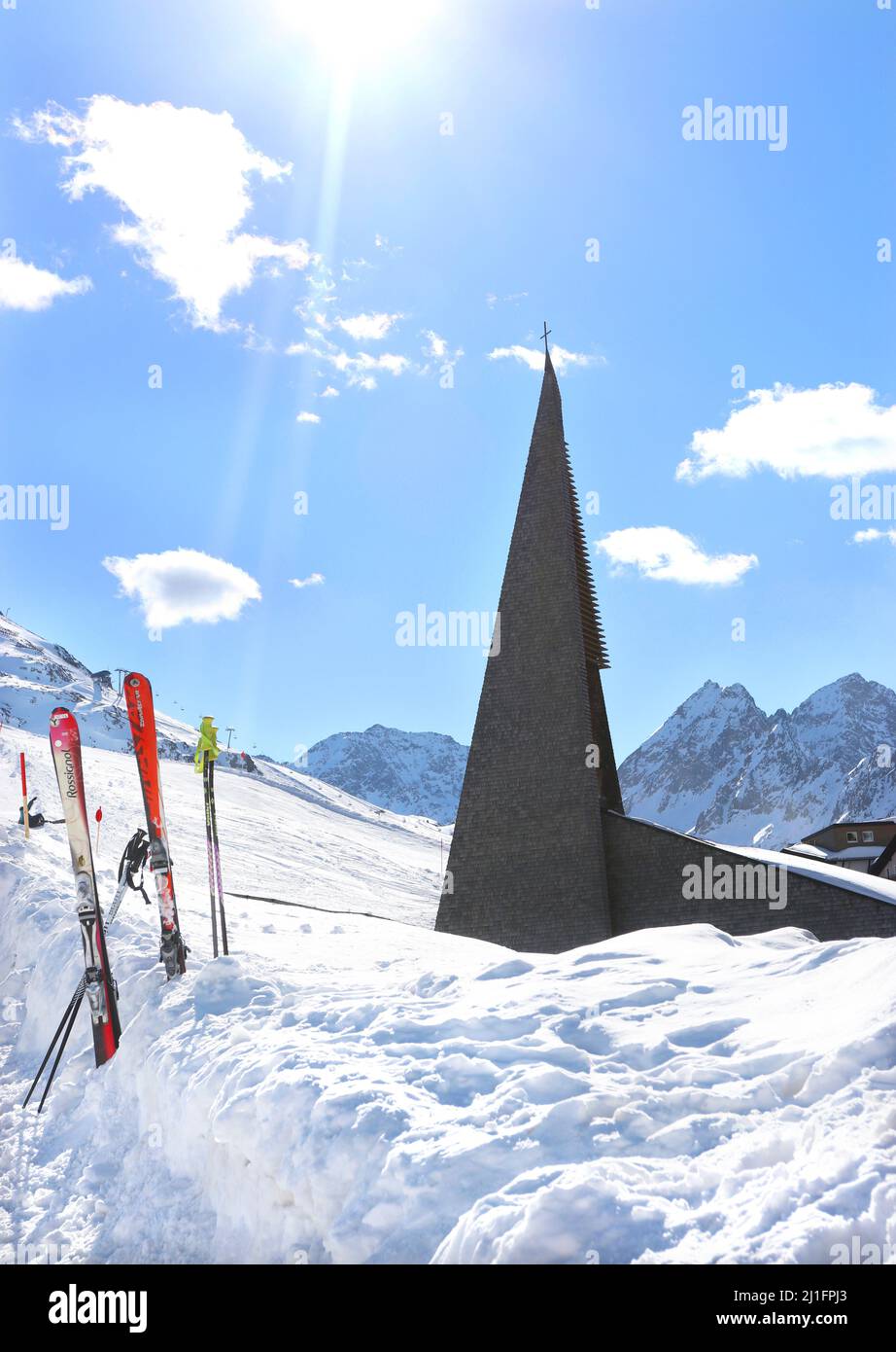 L'unico campanile dell'epoca del 1970s della chiesa cattolica romana di Kuhtai si distingue in giustapposizione agli sci e alle piste da sci tra le quali si trova Foto Stock