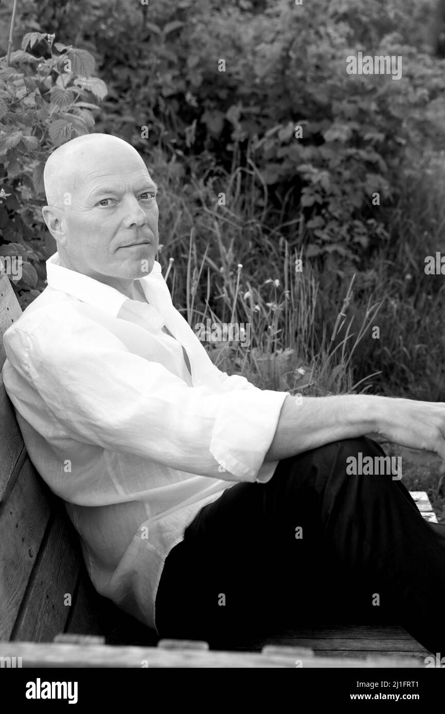 ritratto di bel calvo uomo seduto in giardino. Foto in bianco e nero Foto Stock
