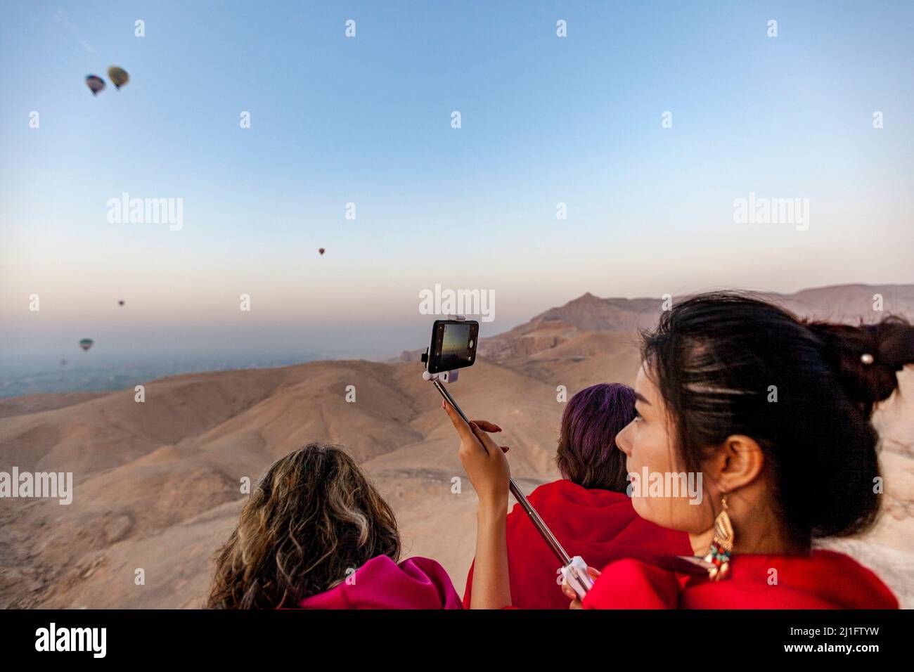 Bella giovane donna in rosso che prende selfie mentre vola in una mongolfiera a Luxor Foto Stock