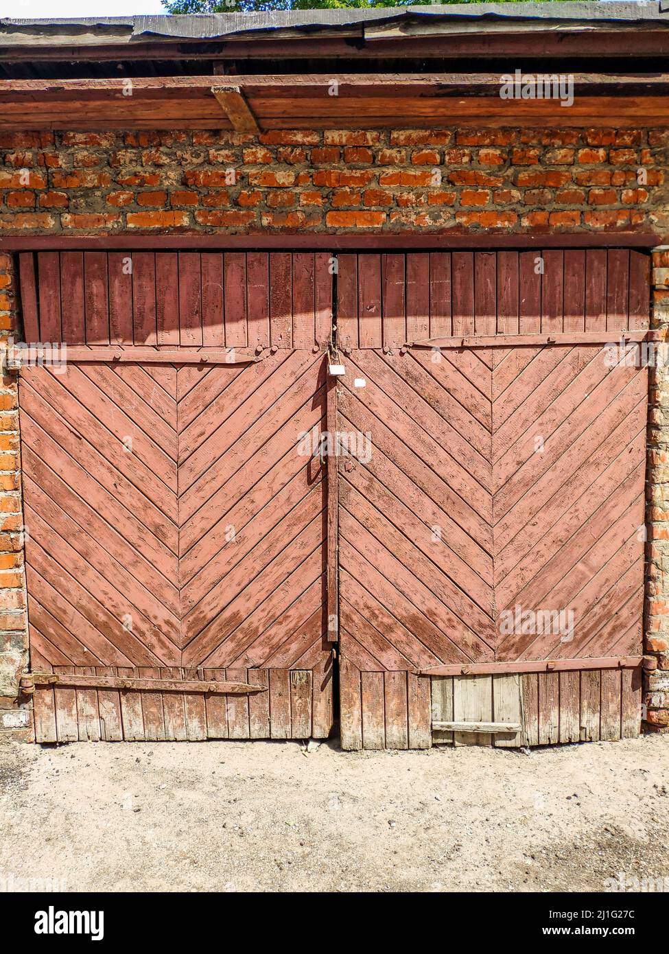 Porta di legno rosa ad un vecchio garage. Foto Stock