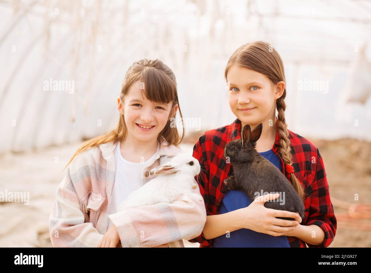 Due ragazze che tengono conigli nelle loro mani. Concetto di Pasqua Foto Stock