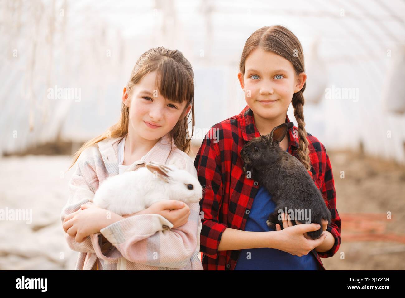 Due ragazze che tengono conigli nelle loro mani. Concetto di Pasqua Foto Stock