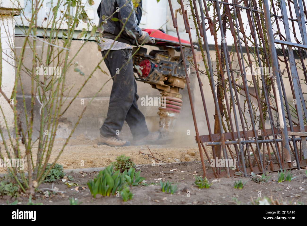 Il lavoratore utilizza un vibratore portatile per costruire un cassero per un'area cieca a casa Foto Stock