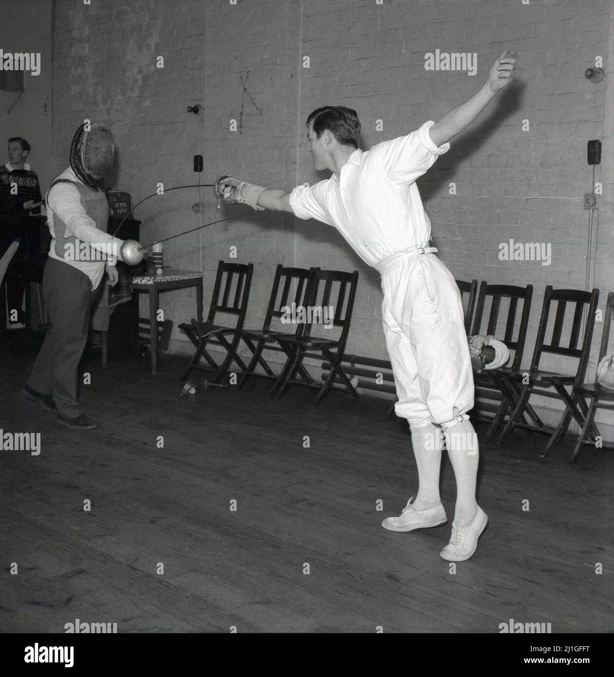 1960s, storico, classe di scherma, all'interno di una sala, uno studente  maschile che indossa tradizionali breches scherma, praticando con un  istruttore o insegnante di scherma, Università di Oxford, Inghilterra,  Regno Unito. Stanno