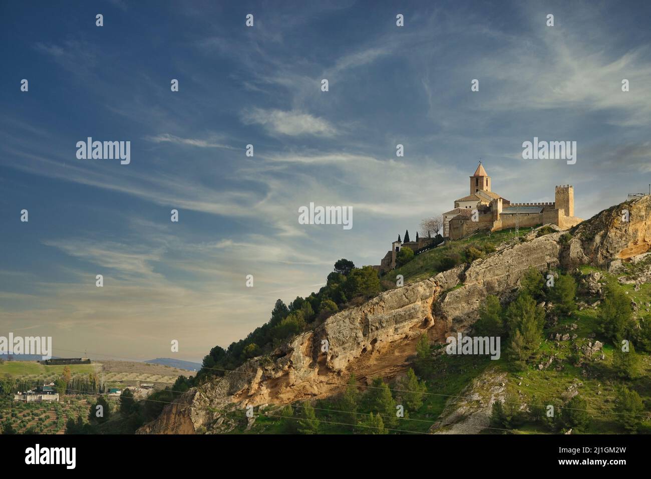 Vista del castello moresco di Iznájar (Córdoba, Spagna) e il campanile della chiesa cristiana di Santiago Apóstol su una collina al tramonto Foto Stock