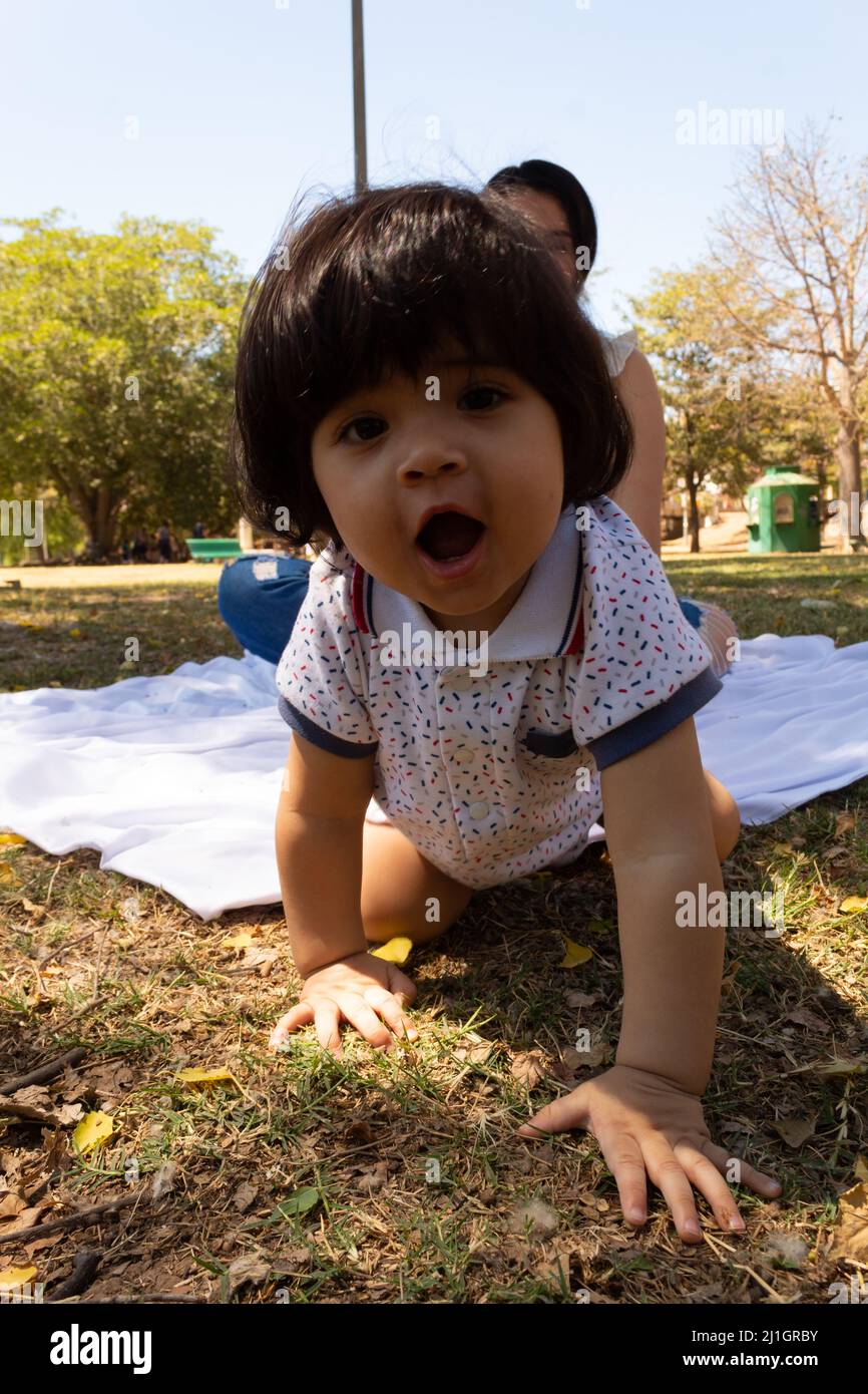 Ritratto divertente di un bambino ispanico strisciando in un parco Foto Stock