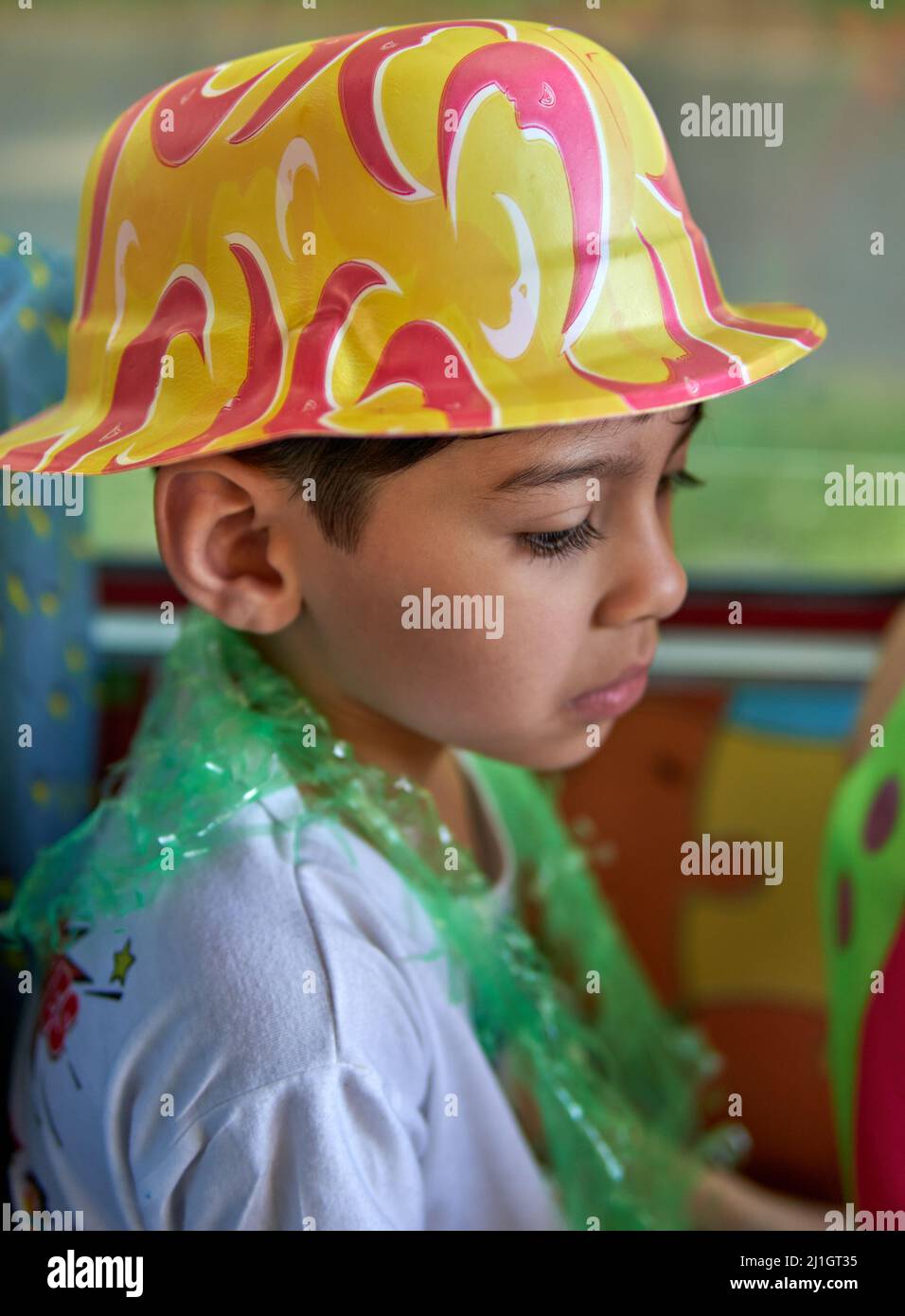 Immagine di deluso ragazzo latino che indossa cappello da festa con triste espressione facciale che guarda in basso. Verticale Foto Stock
