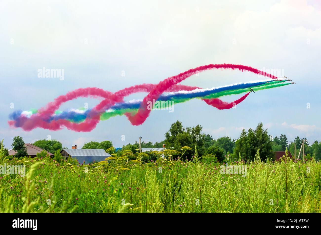 Gruppo di aerei da combattimento con una traccia di fumo colorato contro il cielo Foto Stock
