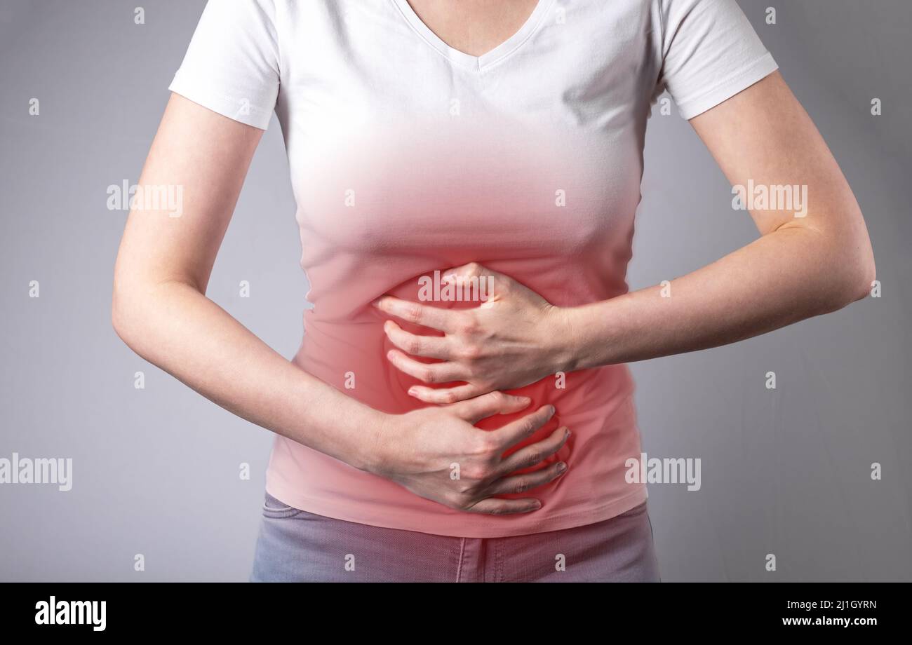 Stomachache. Malattie gastrointestinali. La donna ha mani su stomaco doloroso con punto rosso primo piano. Concetto di assistenza sanitaria e medicina. Foto di alta qualità Foto Stock