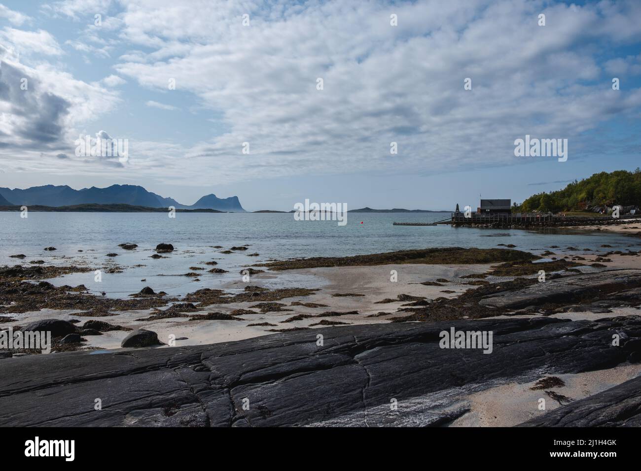 Spiaggia nascosta Senja Island, Norvegia con rocce nere e casa in legno Foto Stock