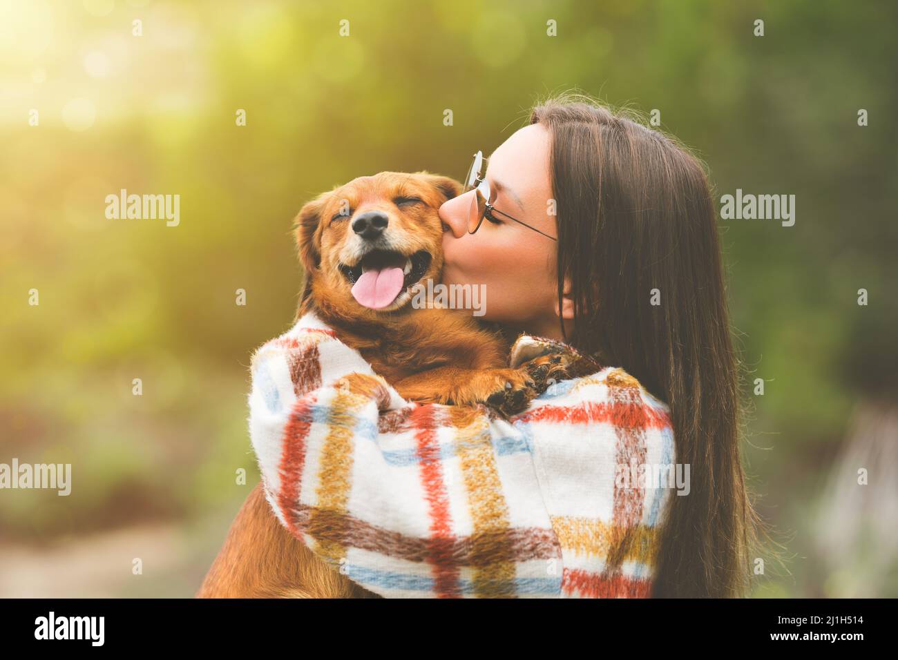Bella donna che abbraccia e bacia il cane. Cane e proprietario insieme all'aperto. Amore e amicizia tra cane e proprietario Foto Stock