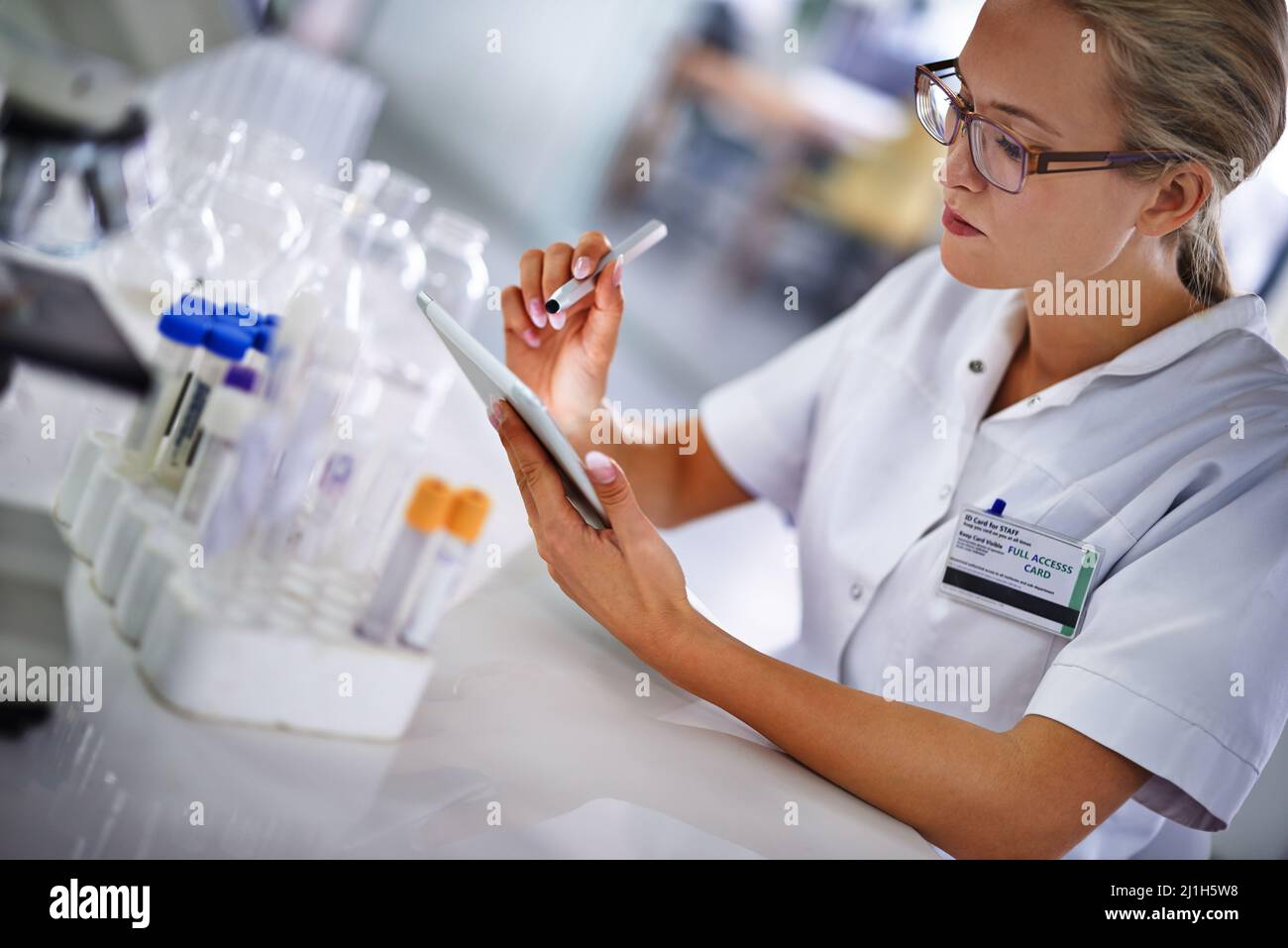 Registrazione dei dati per ulteriori analisi. Un giovane scienziato che lavora a un progetto di ricerca utilizzando un tablet. Foto Stock