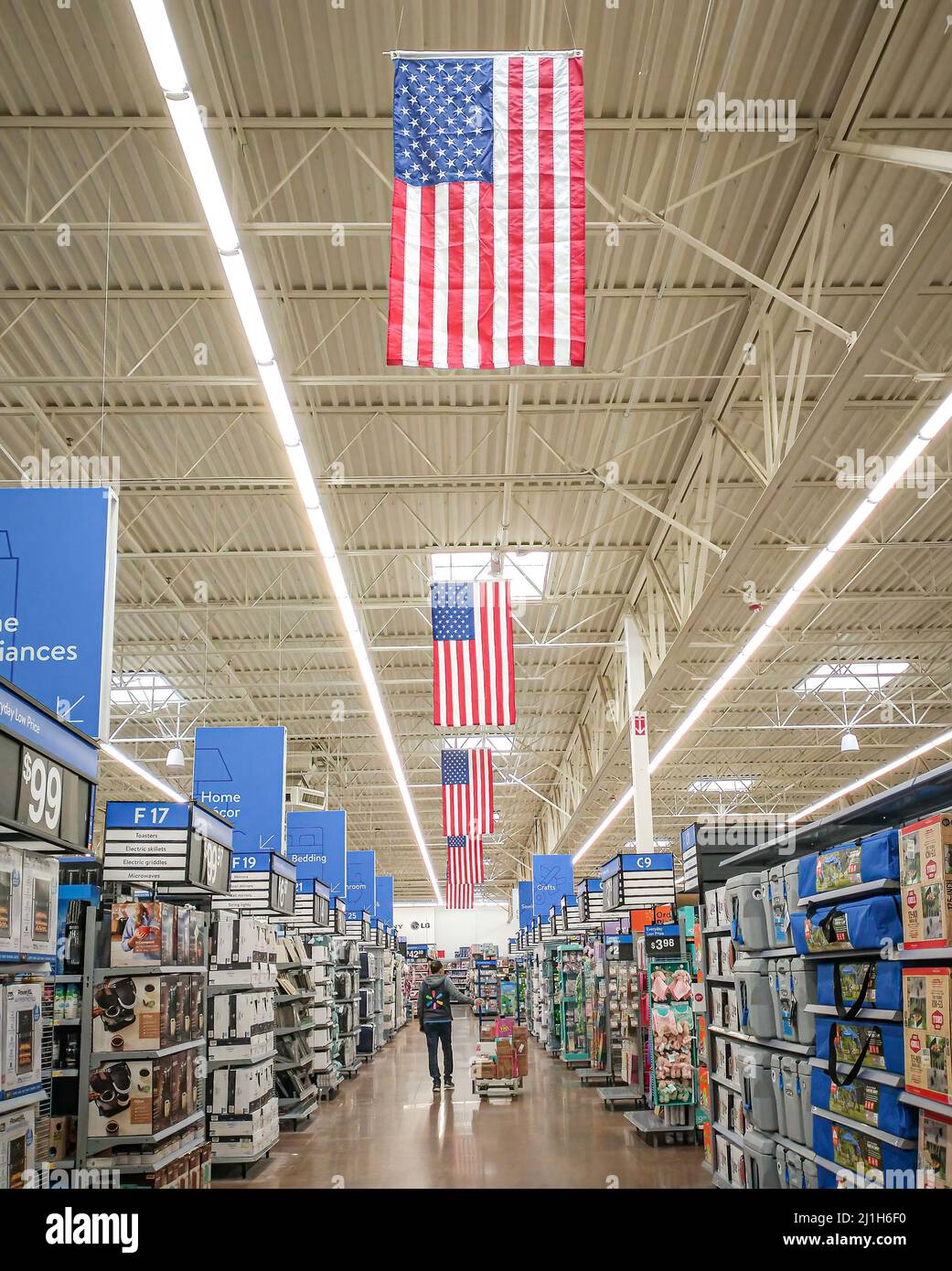 Man Stocking Shelves al Walmart sotto American Flags Foto Stock