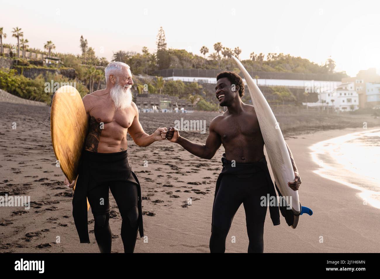 Gente di surfer multirazziale che si diverte sulla spiaggia dopo la sessione di surf - fuoco sul fronte africano dell'uomo Foto Stock