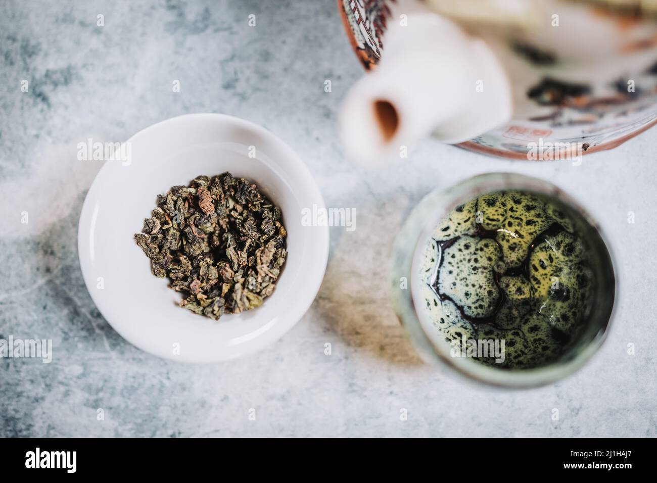 Ora del tè. Teiera, una tazza e tè secco pronto per essere servito, su sfondo grigio. Infusione. Foto Stock