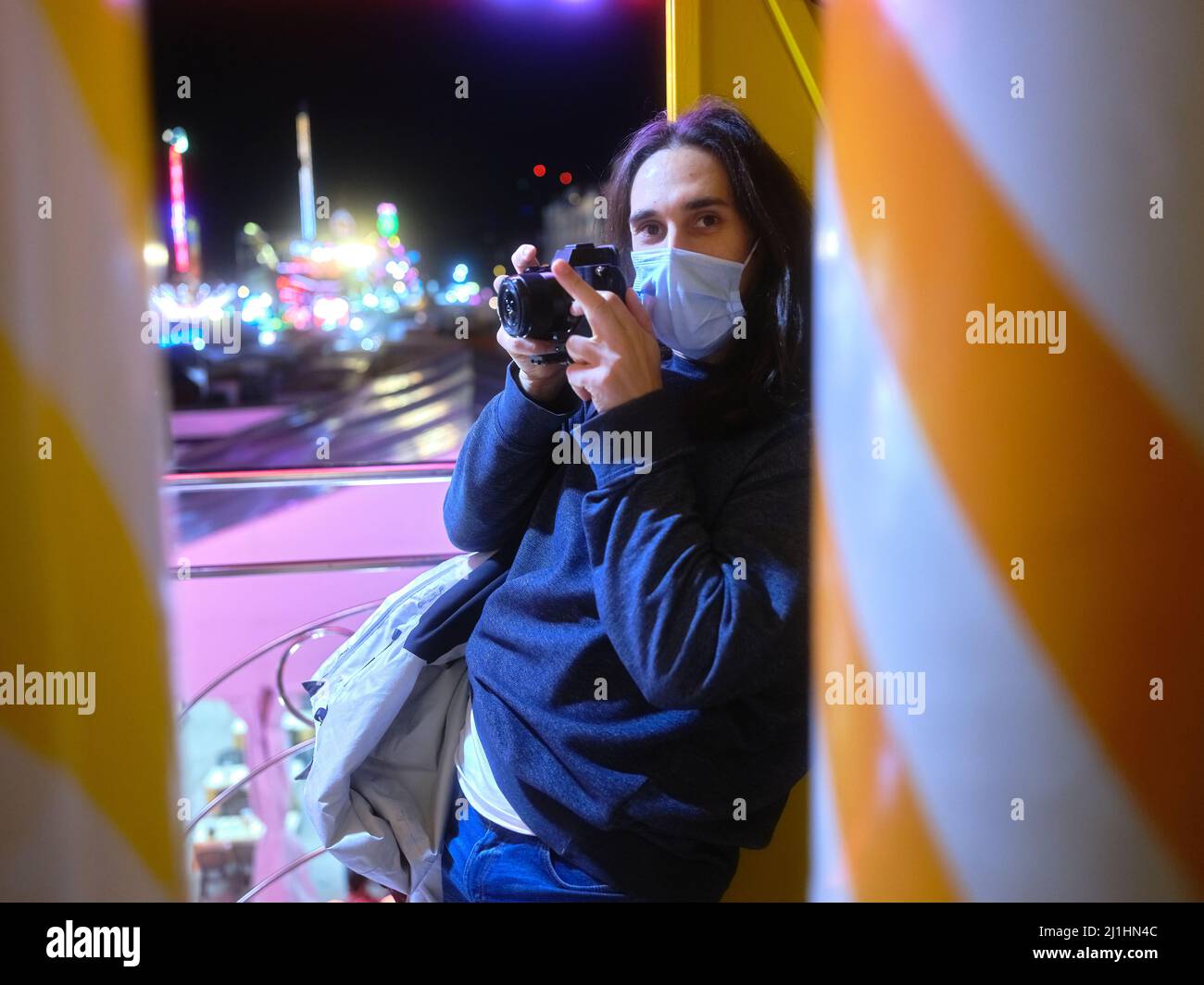 Uomo con una macchina fotografica che si trova sulla colonna di un'attrazione Fairground di notte Foto Stock
