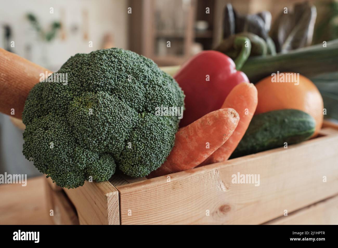 Primo piano di verdure fresche come broccoli, carote, cetrioli e peperoni in scatola di legno Foto Stock