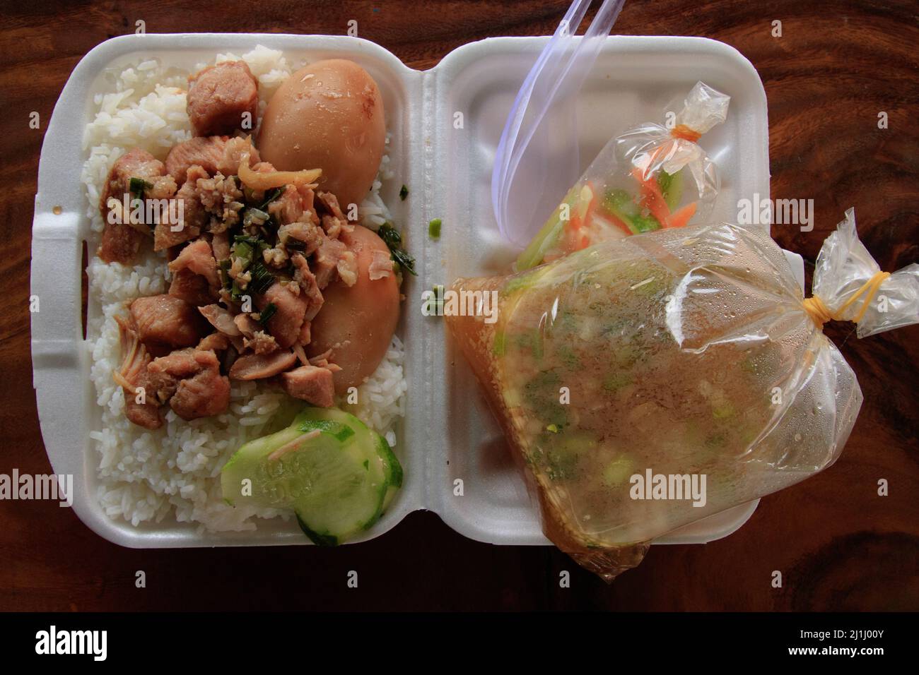 Vista dall'alto del tradizionale cibo khmer chiamato Kaw Sach Chrouk o maiale caramellato con uova confezionate in contenitori di polistirolo tramite servizio di consegna cibo Foto Stock