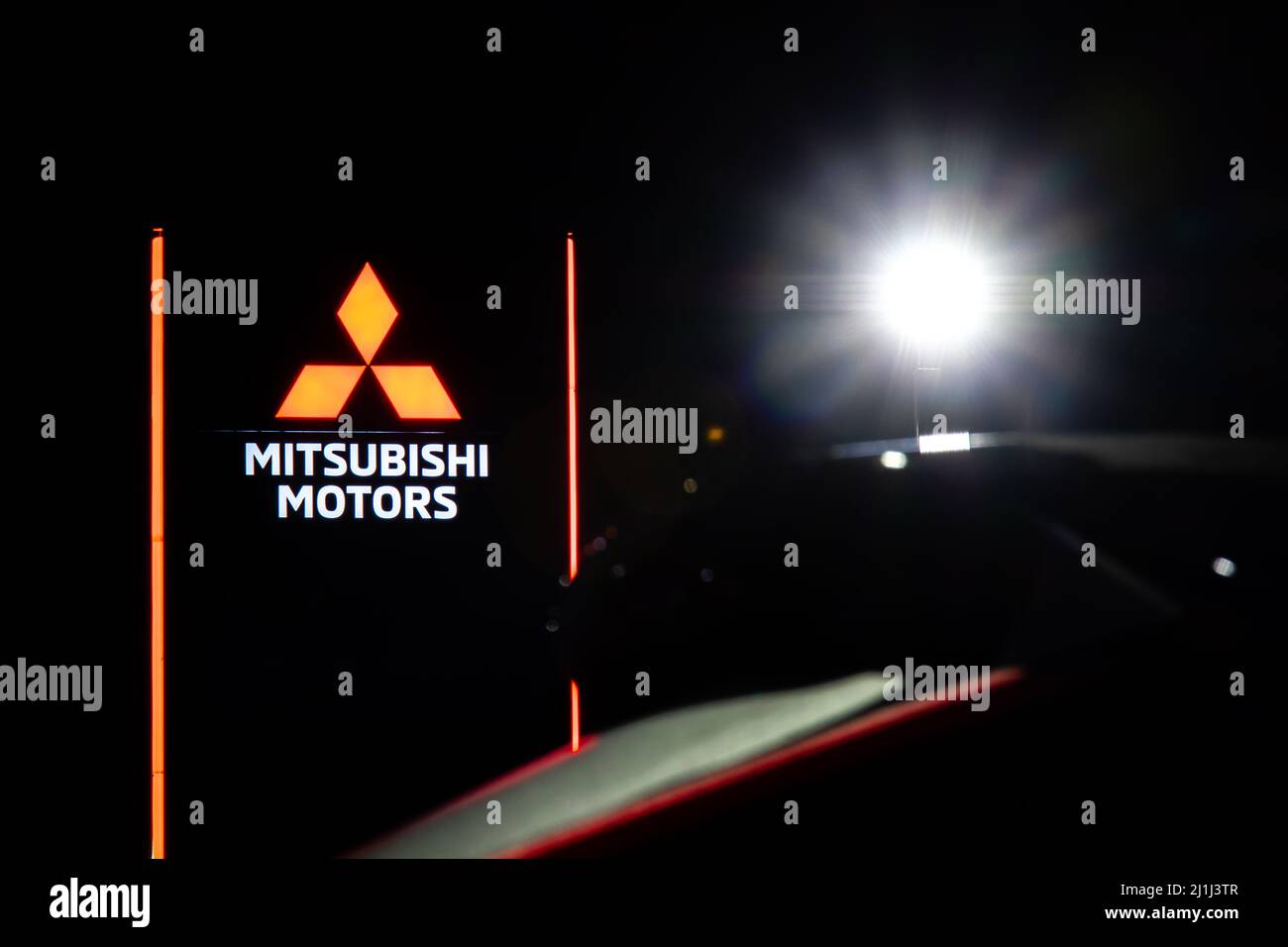 Il logo Mitsubishi Motors è illuminato sul cartello principale presso una concessionaria auto Mitsubishi di recente costruzione di notte. Foto Stock