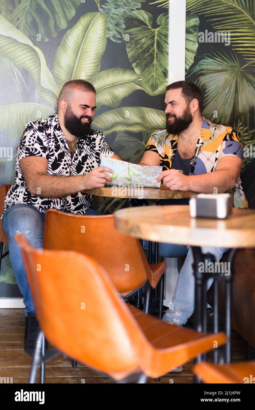 Due gay che pianificano la loro vacanza all'interno di un cocktail bar. Foto Stock